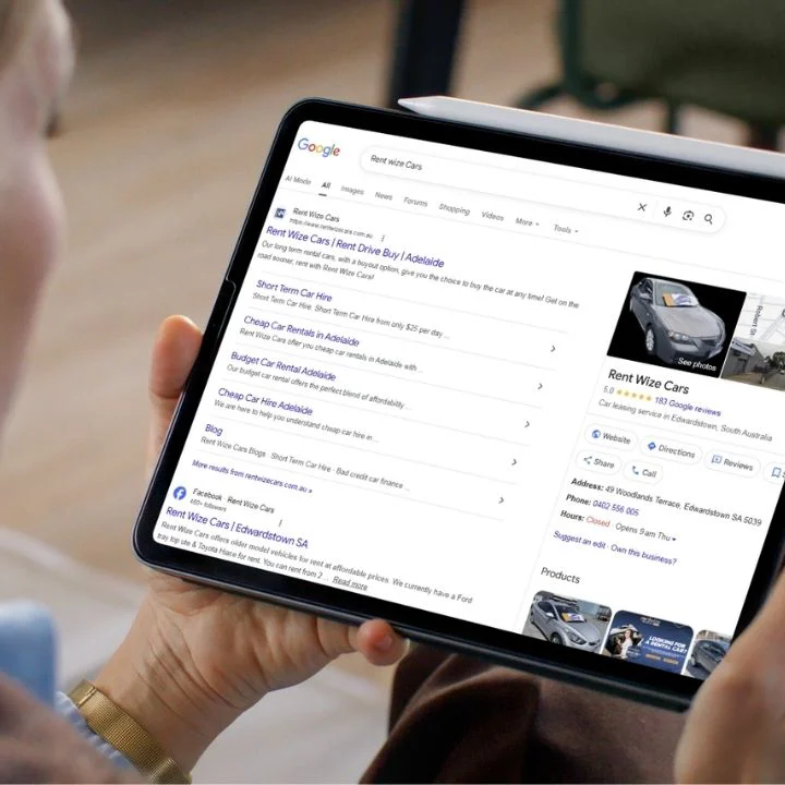 A person holding a tablet showing high Google search rankings for an Australian car rental business, demonstrating Million Hits SEO services.